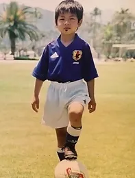 少年時代のオリビエ。青いユニフォームに白い半ズボンを穿き、左足でサッカーボールをおさえている